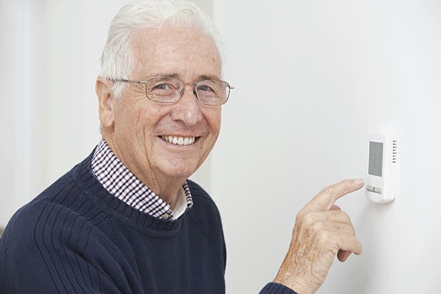 man adjusting thermostat